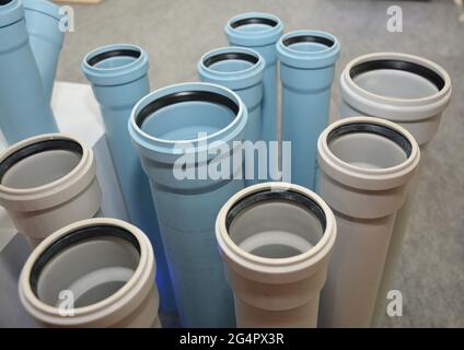 L'esposizione di tubi fognari bianchi e blu in plastica, tubi di scarico sotterranei in un negozio. Scelta dei tubi di scarico fognari in PVC. Foto Stock
