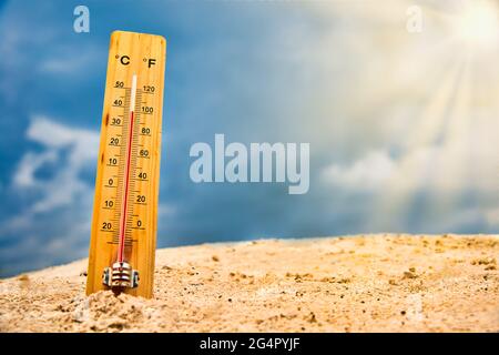 Termometro meteorologico nella sabbia contro il cielo che mostra una temperatura ambiente elevata Foto Stock