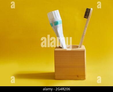 Spazzolino da denti in legno e un tubo di dentifricio in un supporto di legno Foto Stock