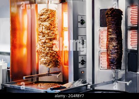 Shawarma kebab turco fresco, carne cotta su uno spiedino elettrico. Foto Stock