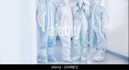 Medici e infermieri del team che indossano maschera protettiva personale e attrezzature in clinica ospedaliera. Banner Concept covid Epidemic. Foto Stock