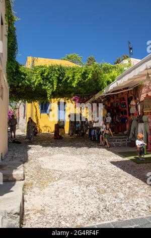 RODI, Grecia - 07 GIUGNO 2021. Una strada laterale della famosa Socrate Street nel centro storico di Rodi con una Casa gialla e un negozio di abbigliamento. Foto Stock