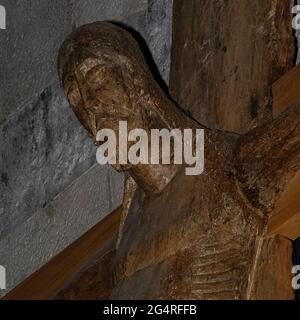 Veduta quadrata dettagliata di un capolavoro di scultura religiosa medievale, un crocifisso scolpito a metà del 1100 da un solido tronco di pioppo, con le braccia aggiunte in legno di ontano, appeso nella Chiesa di Santa Maria del Tiglio, un ex battistero romanico a Gravedona, in Lombardia, in Italia. Sebbene possa essere lombardo, è più tipico della scultura francese o tedesca e un crocifisso simile in bronzo è conservato nel monastero benedettino di Werden vicino a Essen nella Ruhr, Germania. Foto Stock