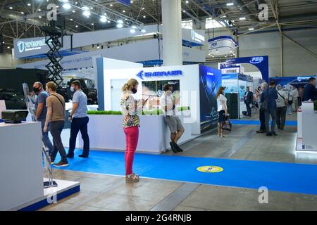 Stand con le merci allestite in una sala, persone visitatori a piedi durante una mostra. Mostra armi e sicurezza. 15 giugno 2021. Kiev, Ucraina Foto Stock