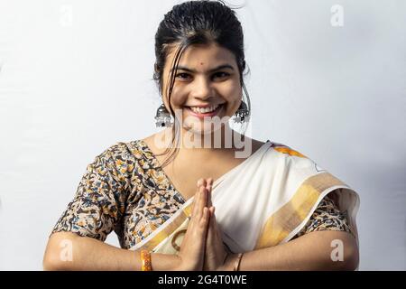 Una bella donna indiana in saree isolate su sfondo bianco accoglie in posa namaste con volto sorridente Foto Stock