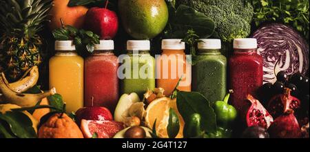 Succhi colorati in bottiglie con frutta, verdure e verdure intorno Foto Stock