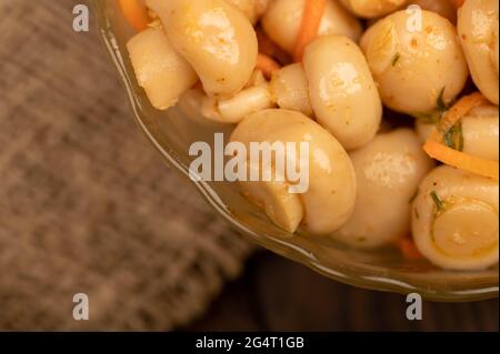 Funghi salati in un piatto di vetro su un tavolo di legno. Primo piano fuoco selettivo Foto Stock