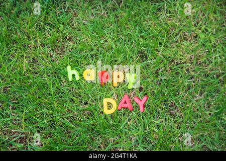 happy day scritta con lettere giocattolo sull'erba nel giardino della casa Foto Stock