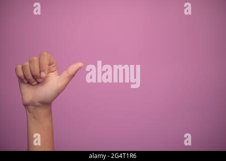Mano che mostra i pollici verso l'alto gesto su sfondo rosa Foto Stock