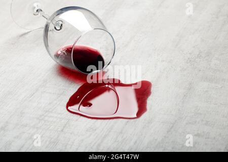 Pavimento in legno con bicchiere rovesciato di vino rosso. Vino versato su un pavimento in parquet laminato di legno con protezione contro l'umidità. Foto di alta qualità Foto Stock