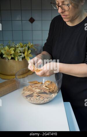 Lei sta sgretolando i biscotti. Sta facendo una torta di compleanno con biscotti e cioccolato. Torta a mosaico. Buon compleanno. Foto Stock