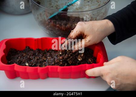 Lei sta sgretolando i biscotti. Sta facendo una torta di compleanno con biscotti e cioccolato. Torta a mosaico. Buon compleanno. Foto Stock