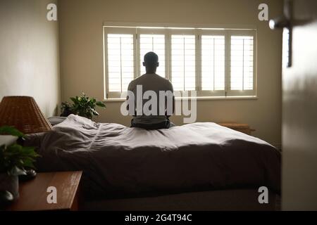 Giovane africano seduto sul letto al mattino Foto Stock
