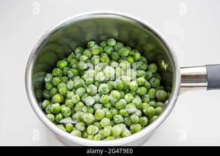 Piselli verdi surgelati in una pentola per bollire Foto Stock