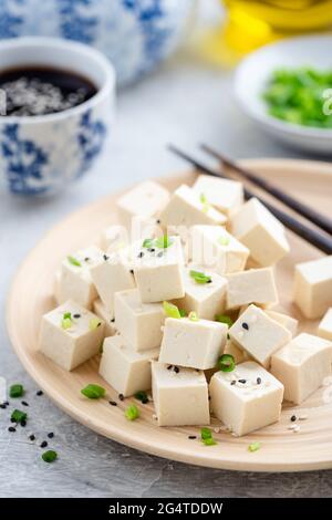 Tofu tagliato a cubetti su un piatto di bambù. Cibo asiatico Foto Stock