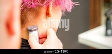 Vicino la mano del parrucchiere rade donna capelli rosa con rasoio elettrico  nel salone di bellezza. Le mani sono la rasatura donna capelli Foto stock -  Alamy