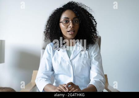 Misto razza donna medico parlare online con il paziente, fare una videochiamata, guardando la fotocamera Foto Stock