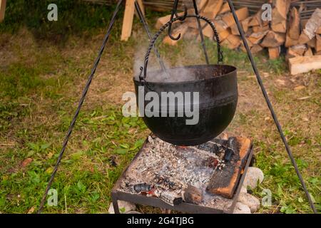 Preparazione di cibo in pentola sospeso su fuoco aperto - concetto di campeggio Foto Stock