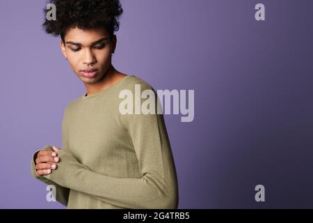 Ritratto di giovane uomo bruna con pelle scura in t-shirt casual. Maschio ispanico su sfondo viola Foto Stock