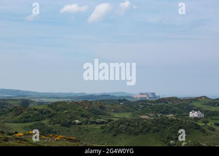 La centrale nucleare di Magnox decommissionata a Wylfa, vista in lontananza mentre si cammina lungo il sentiero costiero dell'isola di Anglesey dalla baia di Cemaes. Foto Stock