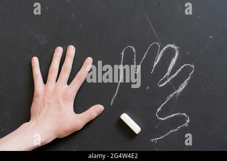 tenere a mano un pezzo di gesso e disegnare un circuito di altra mano Foto Stock