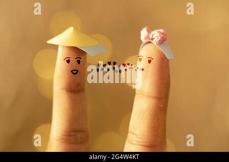 Scatto creativo di una coppia felice disegnata sulle dita con le luci di bokeh gialle sullo sfondo Foto Stock