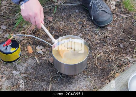 Cibo turistico in attività all'aperto. Zuppa nella foresta per gli alberi. Camping alimentare fare in viaggio. Foto Stock