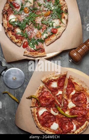 Pepperoni e Mozzarella Pizza vista dall'alto con tritatutto per pizze su fondo grigio argilloso Foto Stock