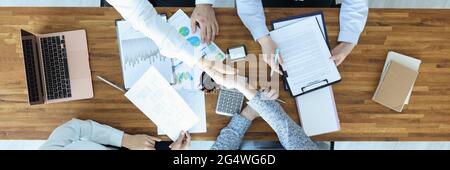 Gruppo di persone che si siedono al tavolo e scuotono la parte superiore delle mani visualizza Foto Stock