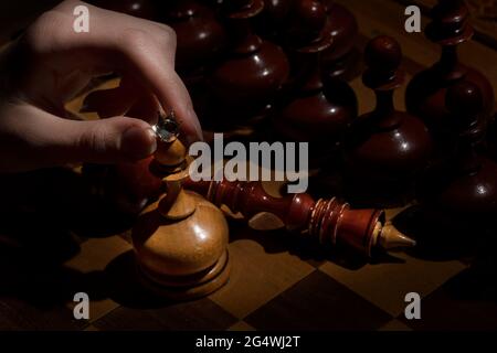 la mano femminile tiene una pedina con una corona su uno sfondo scuro. scacchi vecchi. concetto di business Foto Stock