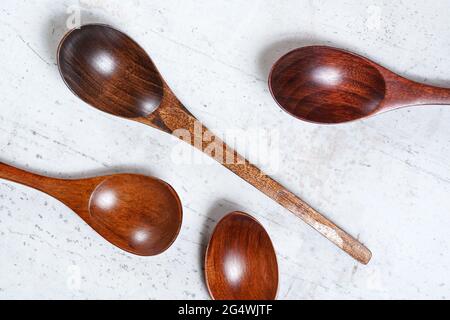 Cucchiai piccoli in legno scuro, su tavola da lavoro bianca, vista dall'alto Foto Stock