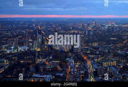 Vista aerea del sud-ovest di Londra, ora blu subito dopo il tramonto, luci di strada giallo arancio che iniziano a brillare Foto Stock