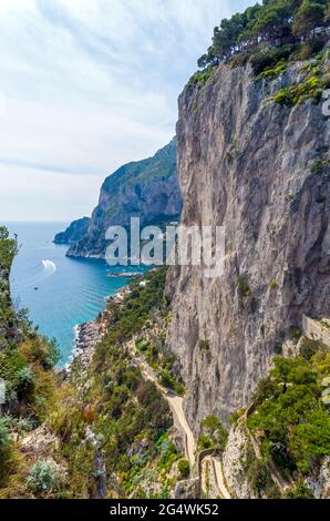 Un magnifico paesaggio dai Giardini di Augusto a Capri. Montagne, rocce, stradina e la barca che passa sullo sfondo, seguita da Foto Stock