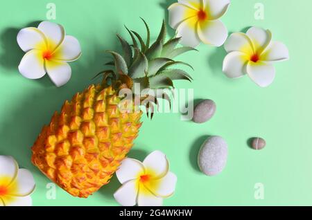 Ananas giallo e fiori bianchi su sfondo blu. Concetto esotico. Foto Stock