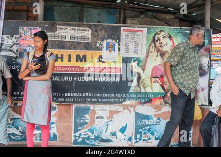 Attraente studente indiano con salwar kameez si alza aspettando alla fermata dell'autobus, Udupi, Karnataka, India Foto Stock