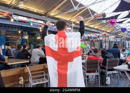 Tifoso inglese con bandiera sulla schiena che guarda il festival UEFA EURO 2020, pub, Greenwich, Londra, Regno Unito Foto Stock