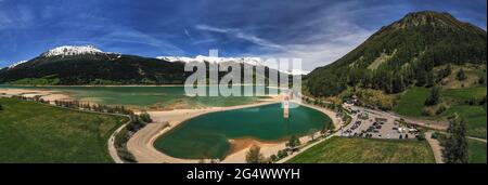 Veduta aerea a 180 gradi del campanile della chiesa sommersa di Curon, Lago di Resia, provincia di Bolzano, Alto Adige, Italia. Foto Stock