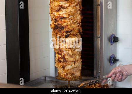 Carne su uno spiedo. Shaurma si sta preparando in una caffetteria. La carne di pollo è strung su uno spiedino elettrico. Foto Stock