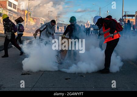 Bogotà, Colombia. 21 Giugno 2021. Un gruppo di dimostranti mitiga un barattolo di gas lacrimogeni mentre a Bogotà, Colombia, gli scontri tra i dimostranti e la polizia malata della Colombia scatenano proteste anti-governative contro il governo del presidente Ivan Duque, disuguaglianze e abusi di autorità da parte della polizia. Credit: Long Visual Press/Alamy Live News Foto Stock