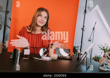 Adolescente ragazza filmare gesturing mentre vlogging make-up tutorial a casa Foto Stock