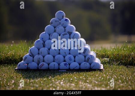 Una piramide solistica di palline da golf al mattino contro uno sfondo verde alberato Foto Stock