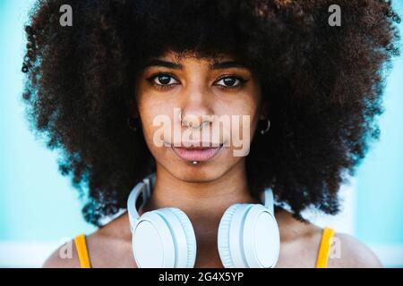 Donna afro che indossa l'anello del naso e le cuffie Foto Stock