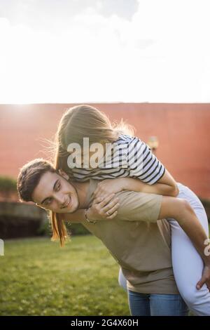 Fidanzata girlfriend piggybacking sul prato il giorno di sole Foto Stock