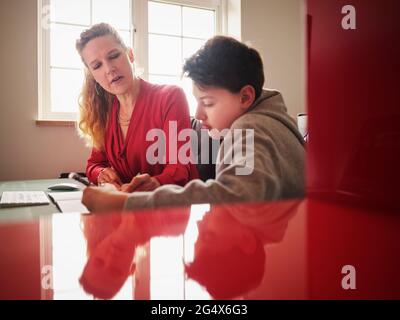 Figlio serio con madre che studia a casa Foto Stock