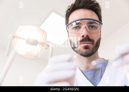 Dentista maschile indossando occhiali protettivi che lavorano in clinica medica Foto Stock