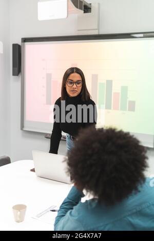 Donna professionista che discute con la collega in ufficio Foto Stock