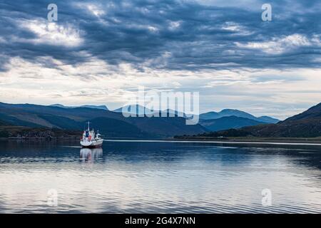 Regno Unito, Scozia, Ullapool, nuvole su una barca da pesca soleggiato che naviga attraverso la baia nelle Highlands scozzesi Foto Stock