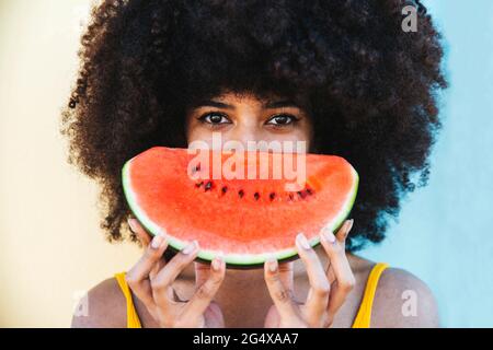 Giovane donna afro che tiene fetta di anguria Foto Stock