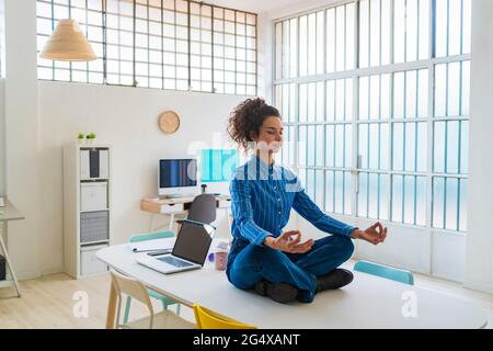 Donna imprenditore meditando mentre si siede in ufficio Foto Stock