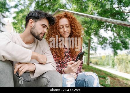 Giovane coppia che usa lo smartphone insieme in parcheggio Foto Stock